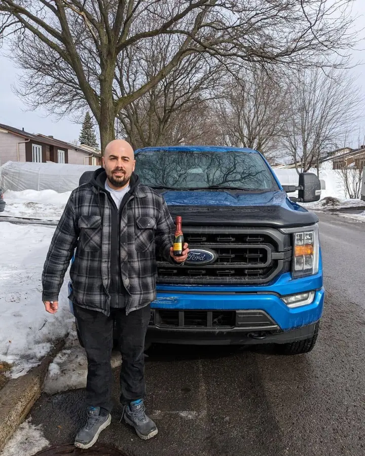 Client devant son Ford F-150 bleu vendu à En Ligne Autos